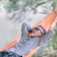 Man enjoying afternoon sleeping in hammock near the water